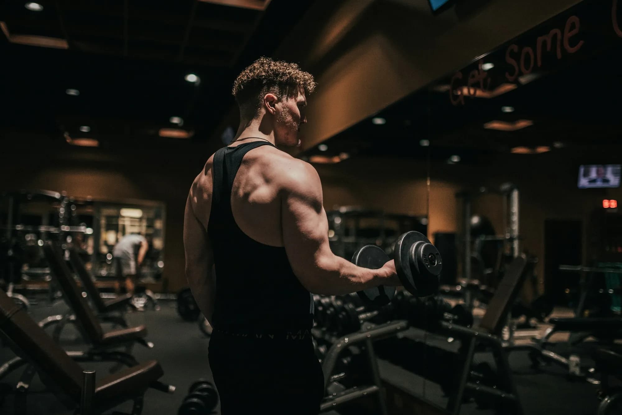 Atleta treinando musculação com halteres na academia